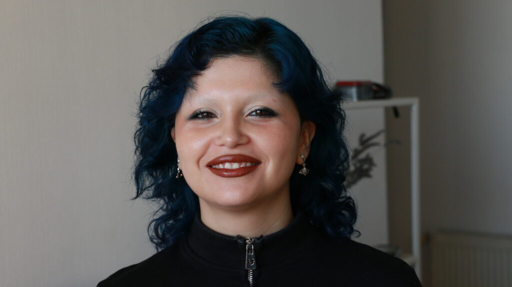 Retrato de Sappho Alexa, persona no binaria, sonriendo.